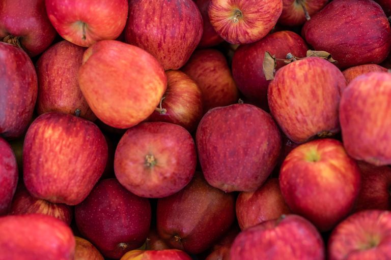 A close-up view of fresh red apples piled together, showcasing their vibrant color and texture.