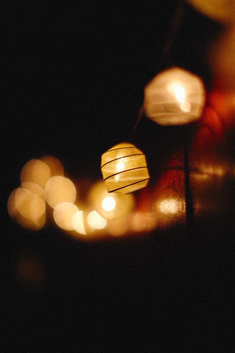 A serene night scene of illuminated paper lanterns with a bokeh effect against a dark background.