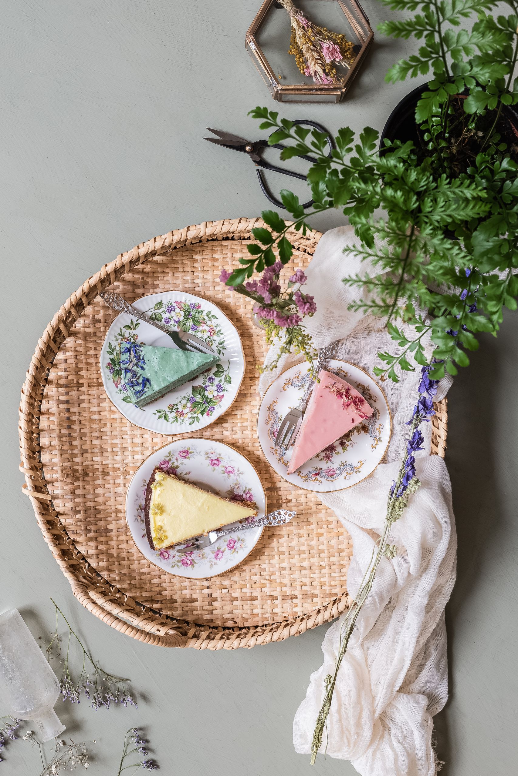 Delicious pastel cake slices on floral plates with greenery and flowers, perfect for dessert themes.
