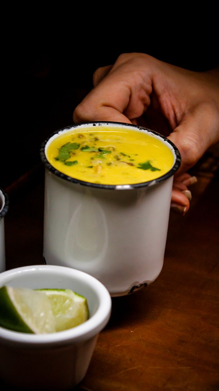 Hand holding cup of turmeric milk with lime side dish, perfect for health and immunity.