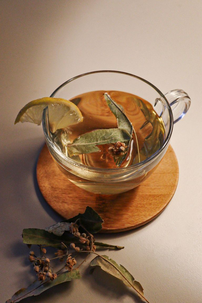 Warm herbal tea with a lemon slice and leaves on a wooden coaster, captured in İstanbul.